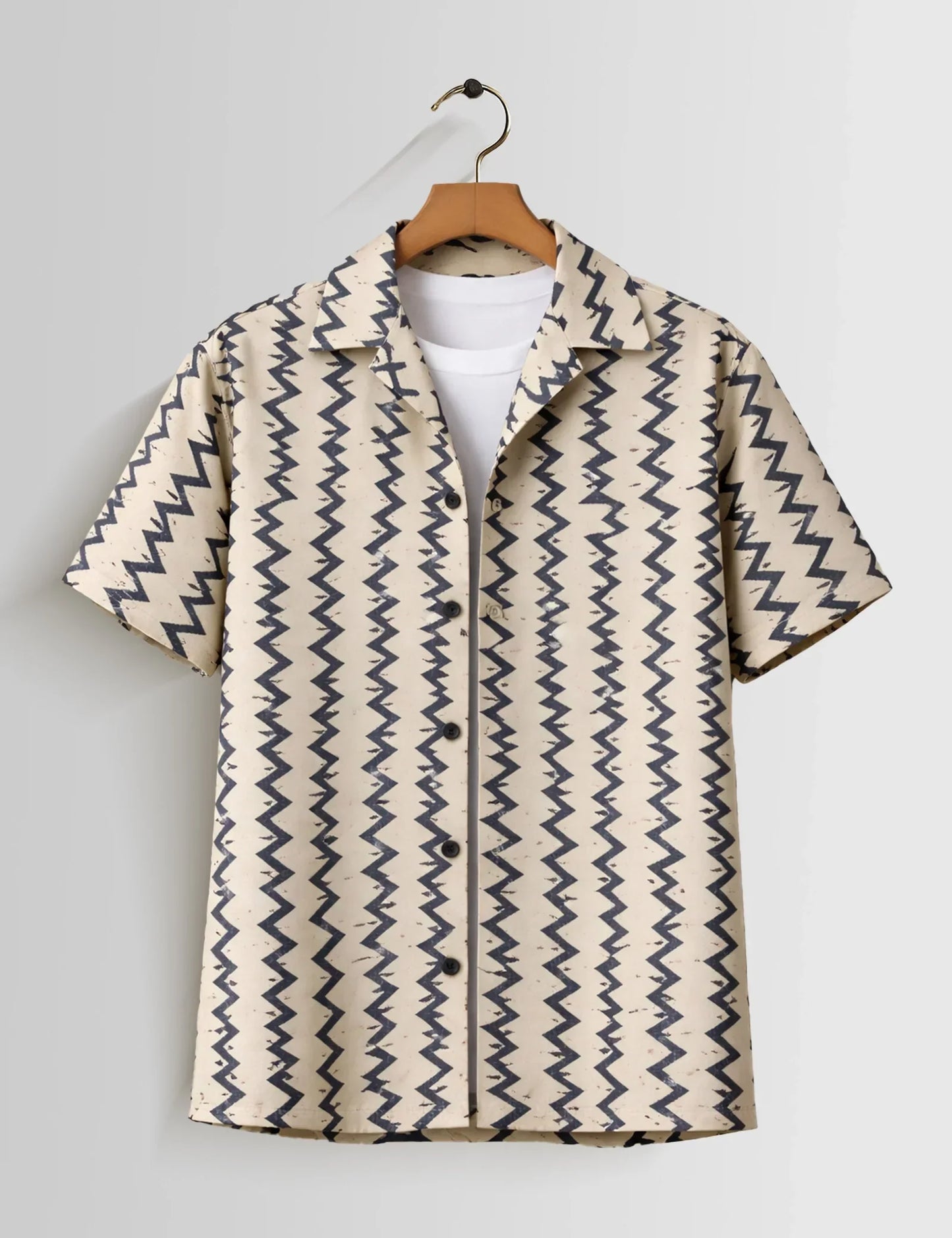 Beige shirt with blue zigzag pattern on a hanger against a white background