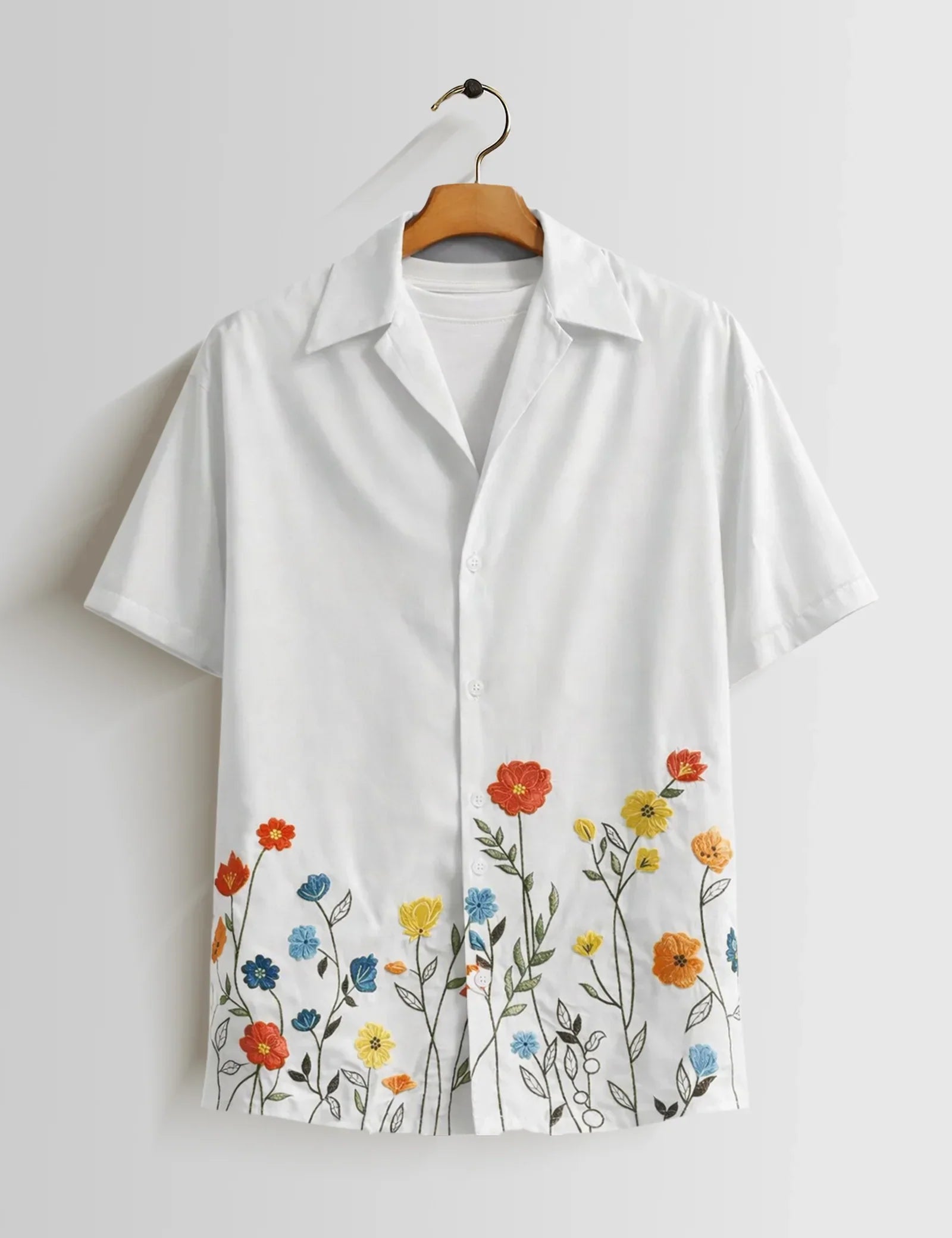 White shirt with floral embroidery on a hanger against a white background